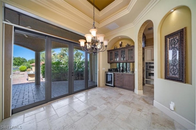 interior space with hanging light fixtures, a raised ceiling, wine cooler, crown molding, and stainless steel double oven