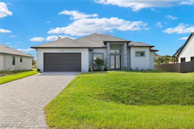 prairie-style home featuring a garage, stucco siding, decorative driveway, and french doors