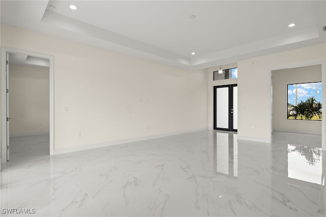 empty room with a raised ceiling, recessed lighting, baseboards, light marble finish floors, and french doors
