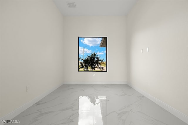 empty room featuring marble look tiles and baseboards