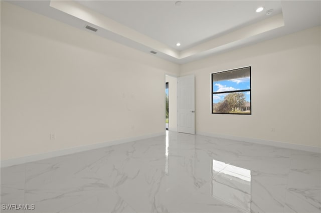 spare room with a raised ceiling, baseboards, recessed lighting, and marble look tiles