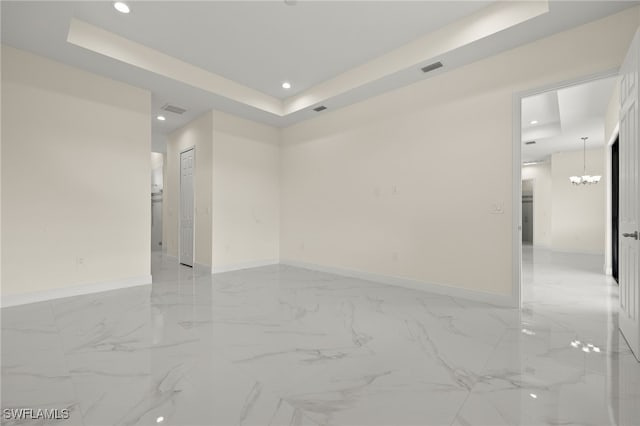 spare room with a tray ceiling, recessed lighting, baseboards, a chandelier, and light marble finish flooring