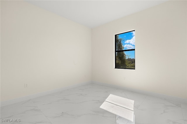 empty room with baseboards and marble look tiles