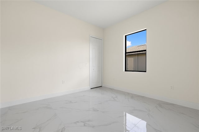 empty room featuring baseboards and light marble finish floors