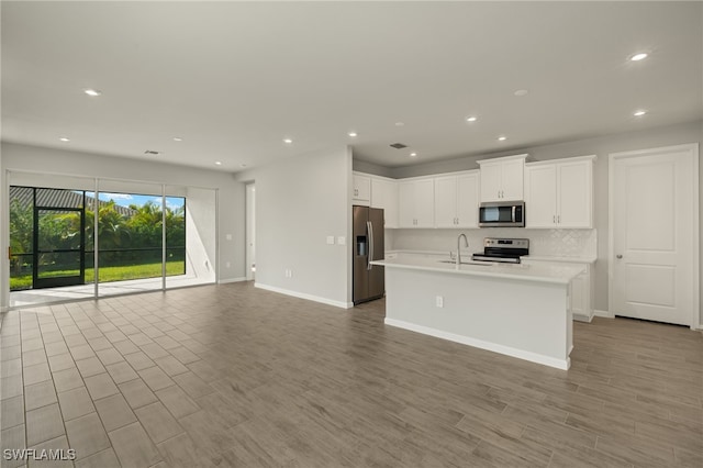 kitchen with a center island with sink, white cabinetry, stainless steel appliances, and light hardwood / wood-style flooring