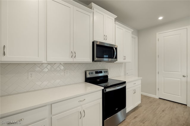 kitchen with decorative backsplash, white cabinetry, light hardwood / wood-style floors, and appliances with stainless steel finishes