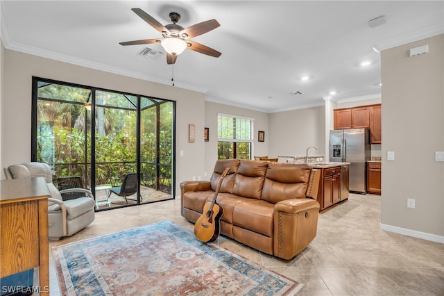 living room featuring ceiling fan, crown molding, and sink