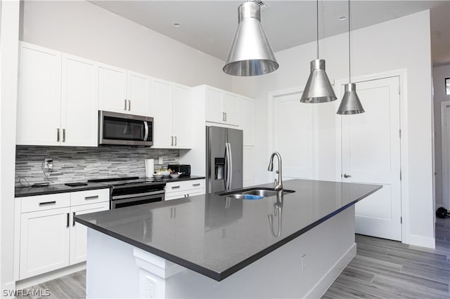 kitchen featuring appliances with stainless steel finishes, white cabinetry, backsplash, and a center island with sink