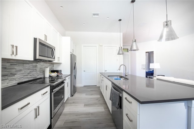 kitchen with stainless steel appliances, backsplash, hanging light fixtures, sink, and white cabinetry