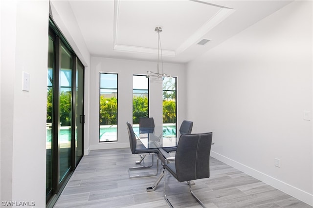 dining room featuring a tray ceiling, light wood-type flooring, and an inviting chandelier