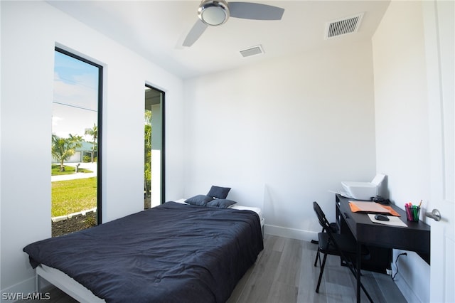 bedroom featuring ceiling fan, multiple windows, and wood-type flooring