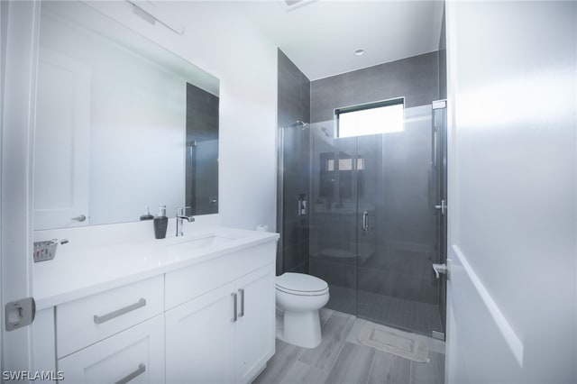 bathroom featuring a shower with door, vanity with extensive cabinet space, and toilet