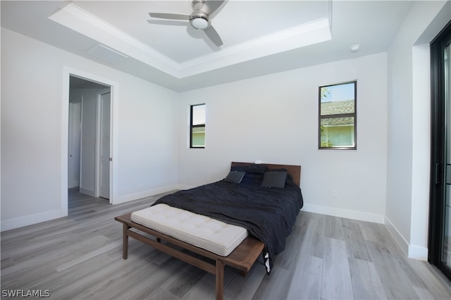 bedroom featuring ceiling fan, a raised ceiling, and light wood-type flooring