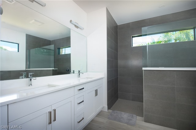 bathroom featuring a tile shower, dual sinks, and vanity with extensive cabinet space