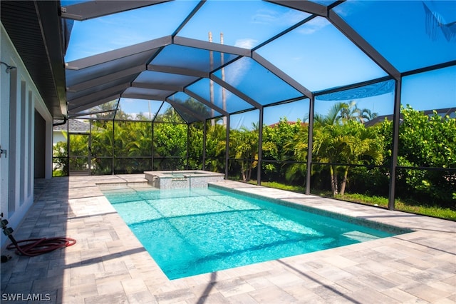 view of pool featuring a patio area, glass enclosure, and an in ground hot tub