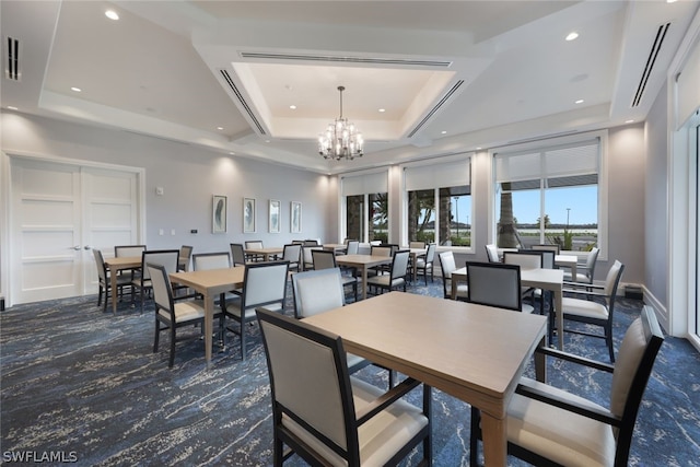 dining area with a raised ceiling and a notable chandelier