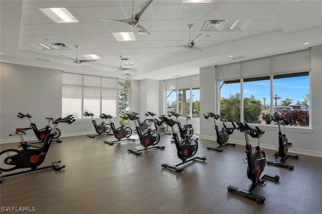 gym with ceiling fan, plenty of natural light, and a paneled ceiling