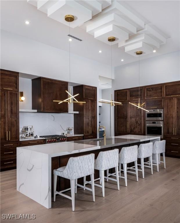 kitchen with a large island, decorative backsplash, stainless steel double oven, and a high ceiling