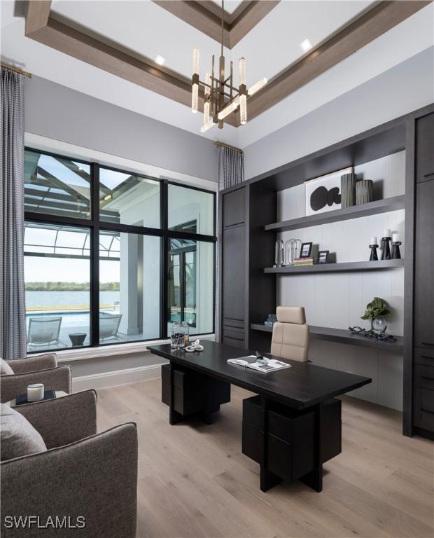 office area with a high ceiling, a chandelier, and light wood-type flooring