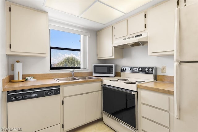 kitchen with sink, light tile patterned floors, white appliances, and cream cabinetry