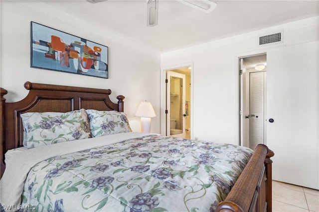 bedroom with light tile patterned floors, a closet, ensuite bathroom, and ceiling fan