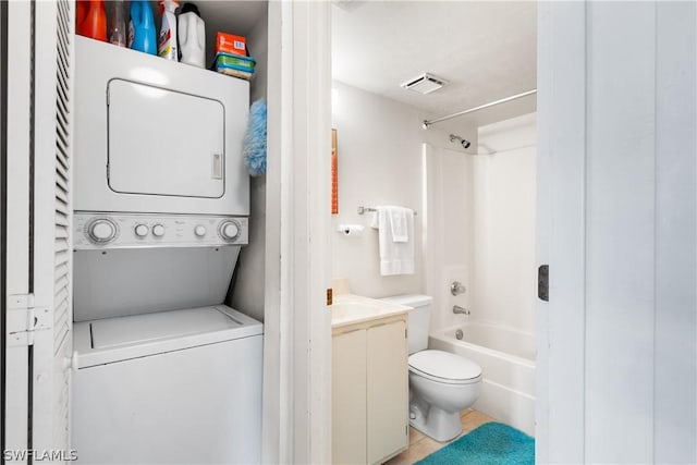 full bathroom featuring tile patterned floors, vanity, washtub / shower combination, toilet, and stacked washer / drying machine