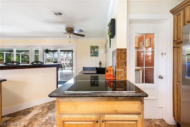 kitchen with ceiling fan, black electric stovetop, a kitchen island, and ornamental molding