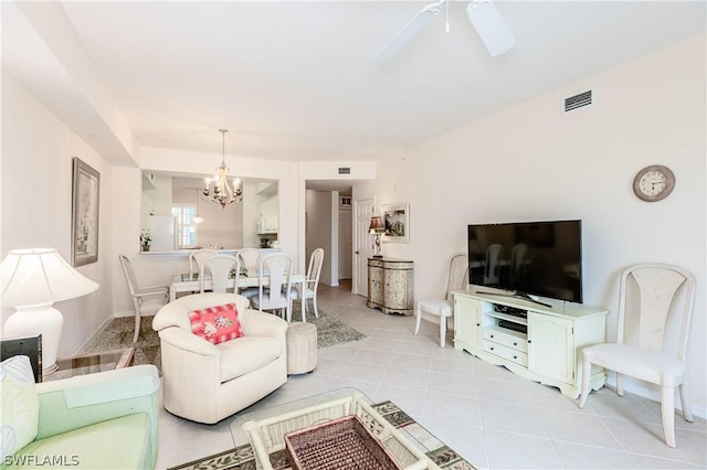 tiled living room with ceiling fan with notable chandelier