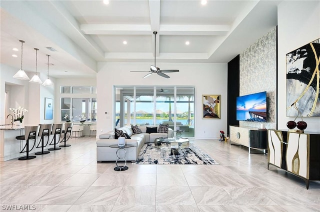 living room with ceiling fan, a towering ceiling, beamed ceiling, and sink