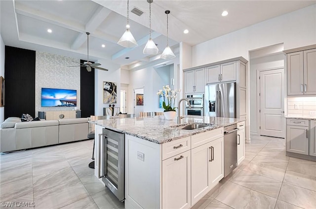 kitchen with ceiling fan, sink, wine cooler, a center island with sink, and appliances with stainless steel finishes