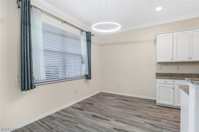 unfurnished dining area featuring light hardwood / wood-style floors and ornamental molding