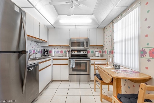 kitchen with white cabinetry, appliances with stainless steel finishes, sink, and a tray ceiling