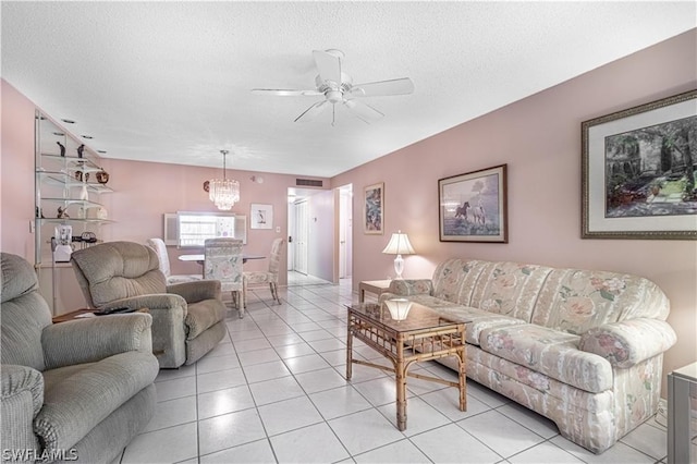 living room featuring ceiling fan with notable chandelier, light tile patterned floors, and a textured ceiling