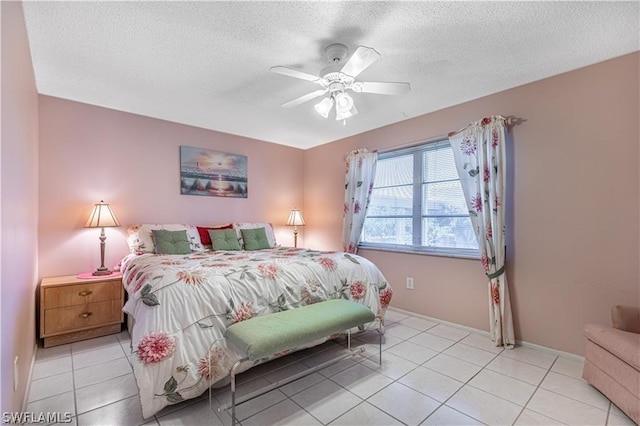 bedroom featuring ceiling fan, light tile patterned floors, and a textured ceiling