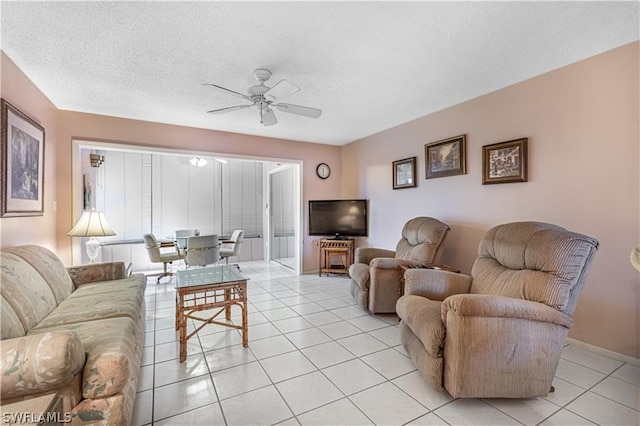 living room featuring ceiling fan, light tile patterned floors, and a textured ceiling