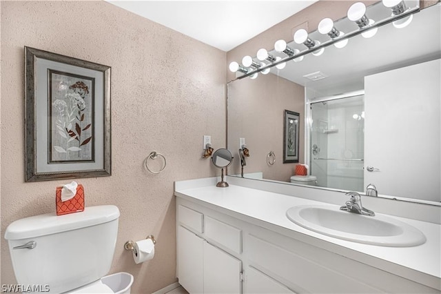 bathroom featuring an enclosed shower, vanity, and toilet