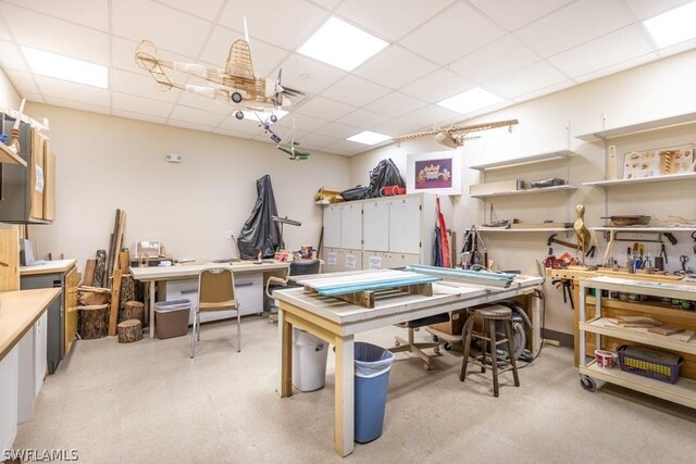 rec room featuring a paneled ceiling and a workshop area