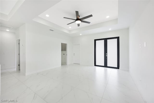 spare room with ceiling fan, french doors, and a tray ceiling