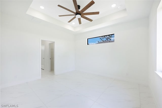 empty room with a raised ceiling and ceiling fan