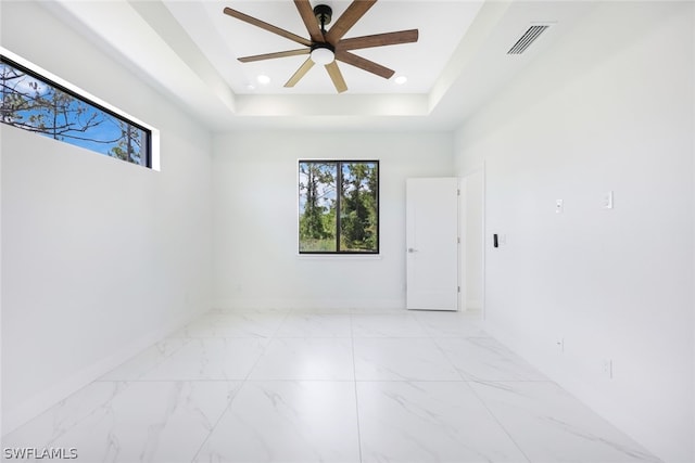 empty room featuring a tray ceiling and ceiling fan