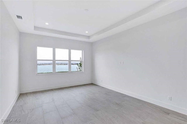 unfurnished room with a water view and a raised ceiling