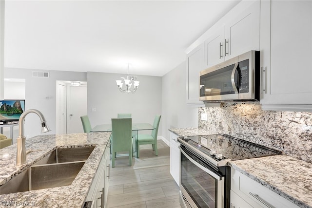 177 Santa Clara Dr Unit 177-4, Naples, FL 34104 - kitchen with white cabinets, sink, light hardwood / wood-style flooring, a notable chandelier, and stainless steel appliances