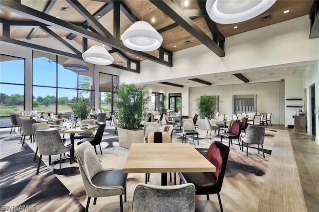 dining area featuring beam ceiling, a high ceiling, and visible vents