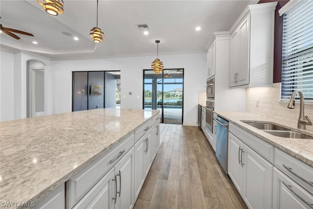 kitchen featuring visible vents, light wood-type flooring, a sink, tasteful backsplash, and white cabinetry