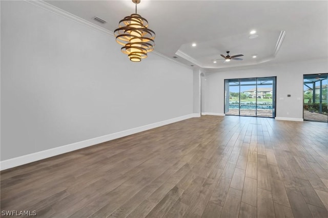 unfurnished room featuring visible vents, wood finished floors, a tray ceiling, and ornamental molding