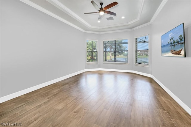 spare room with baseboards, ornamental molding, a raised ceiling, a ceiling fan, and dark wood-style flooring