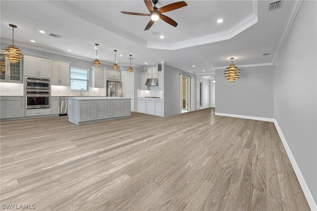 kitchen with visible vents, appliances with stainless steel finishes, a raised ceiling, open floor plan, and backsplash