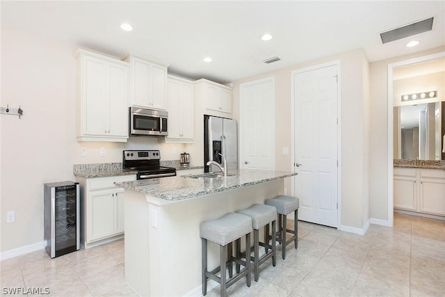 kitchen with a center island with sink, white cabinets, and appliances with stainless steel finishes