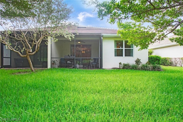 rear view of house with a sunroom, ceiling fan, and a lawn