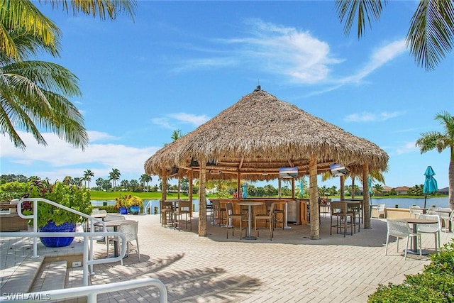 view of property's community with a bar, a water view, a patio area, and a gazebo